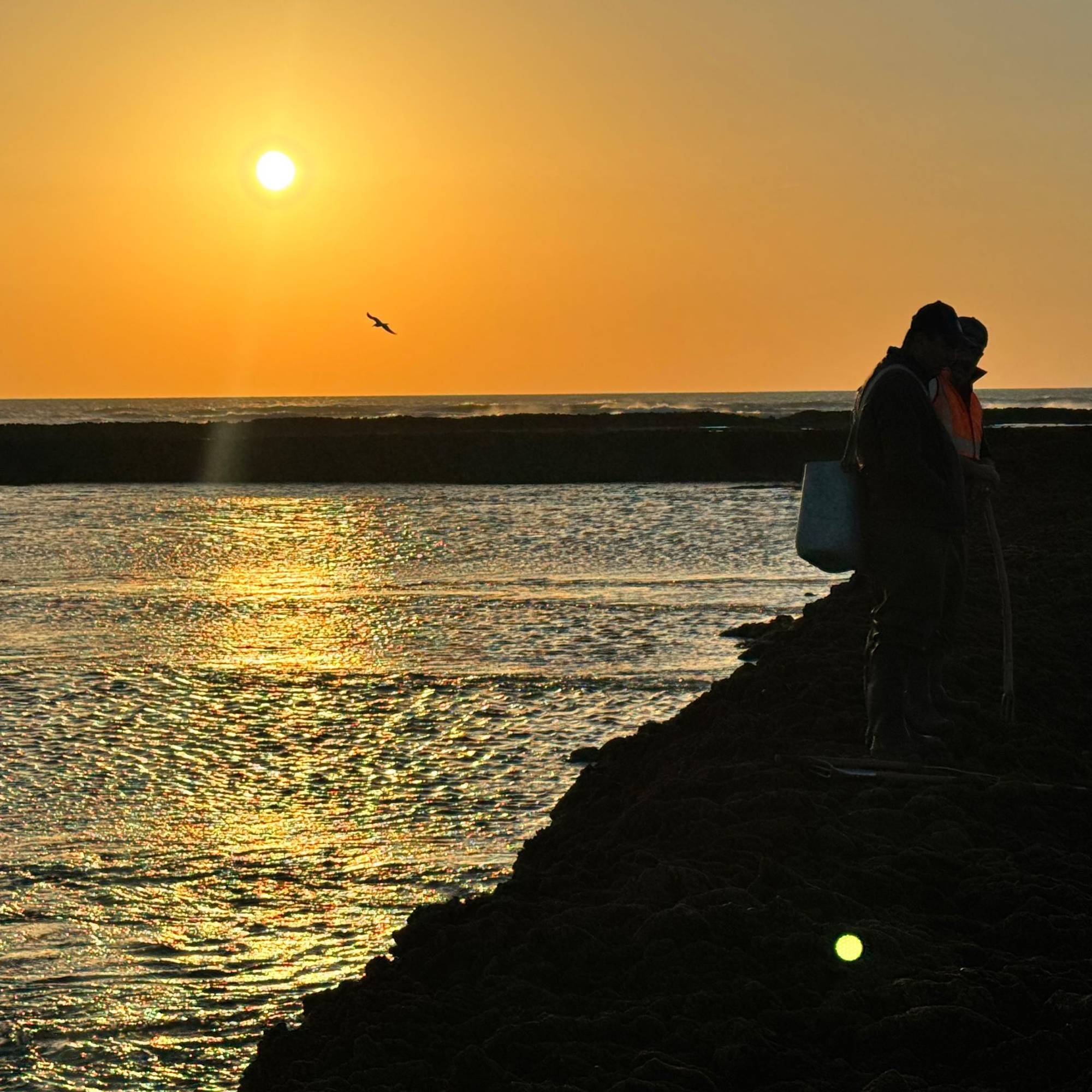 Two corraleros silhouetted on the wall at sunset, carrying buckets