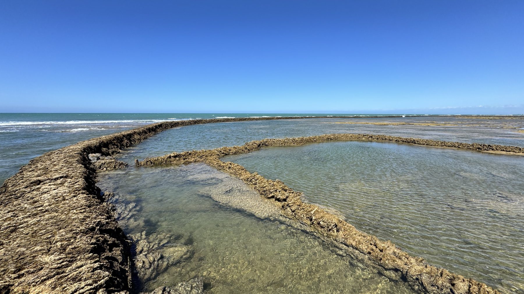 Dry-stone wall of a corral holding back water as the tide falls